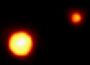 Pluto (links) und sein Mond Charon (rechts) kreisen umeinander. 